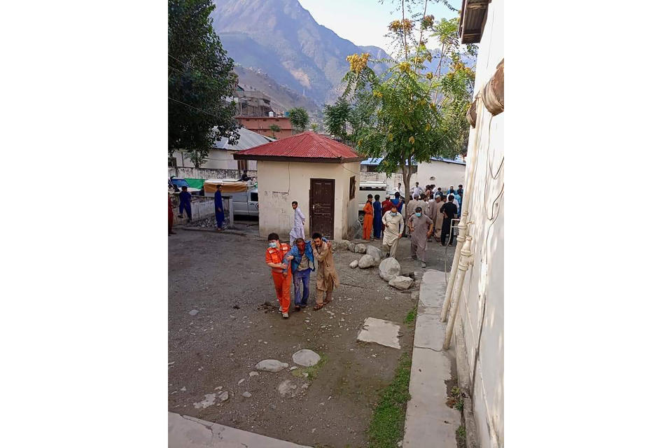 A Chinese national, who was injured in a bus accident, is helped by locals for treatment at a hospital in Kohistan Kohistan district of Pakistan's Khyber Pakhtunkhwa province, Wednesday, July 14, 2021. A bus carrying Chinese and Pakistani construction workers on a slippery mountainous road in northwest Pakistan fell into a ravine Wednesday, killing at least a dozen people, including Chinese nationals, and dozens were injured, a government official said. (AP Photo)