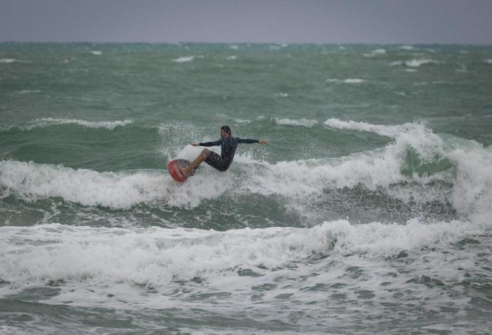 A surfer rides a wave during bad weather on Wednesday, Dec. 13, 2023, in South Miami Beach.