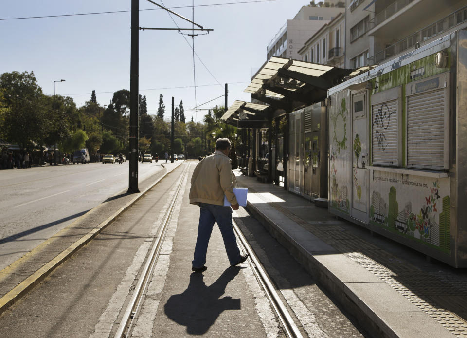 A man walks at a deserted tram stop in central Athens during a strike of the metro and tram networks, in central Athens, Friday, Nov. 9, 2012. Cash-strapped Greece will issue short term debt on Tuesday in the hope of raising enough money to repay a key bond days later. Greece is not expected to get its next batch of international rescue loans by Nov. 16, when it has to roll over euro5 billion in three-month treasury bills. (AP Photo/Dimitri Messinis)