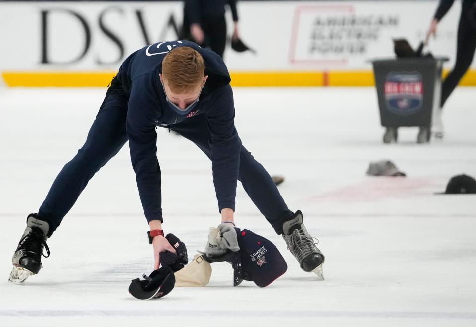 Sun., Mar. 13, 2022; Columbus, Ohio, USA; An Ice Crew member picks up hats following Columbus Blue Jackets center Cole Sillingerâ€™s hat trick during the second period of a NHL game between the Columbus Blue Jackets and the Vegas Golden Knights at Nationwide Arena. 