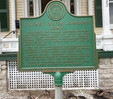 The historical marker for the Johnson-Phinney House in Monroe is shown. Colonel Oliver Johnson built the home in the 1822-1823 time period, and it represents a modified Federal-era design – one of the few in existence in Michigan. The Monroe county Historical Society and the City of Monroe moved it in October, 1977 from the site of the new City Hall to its current location.