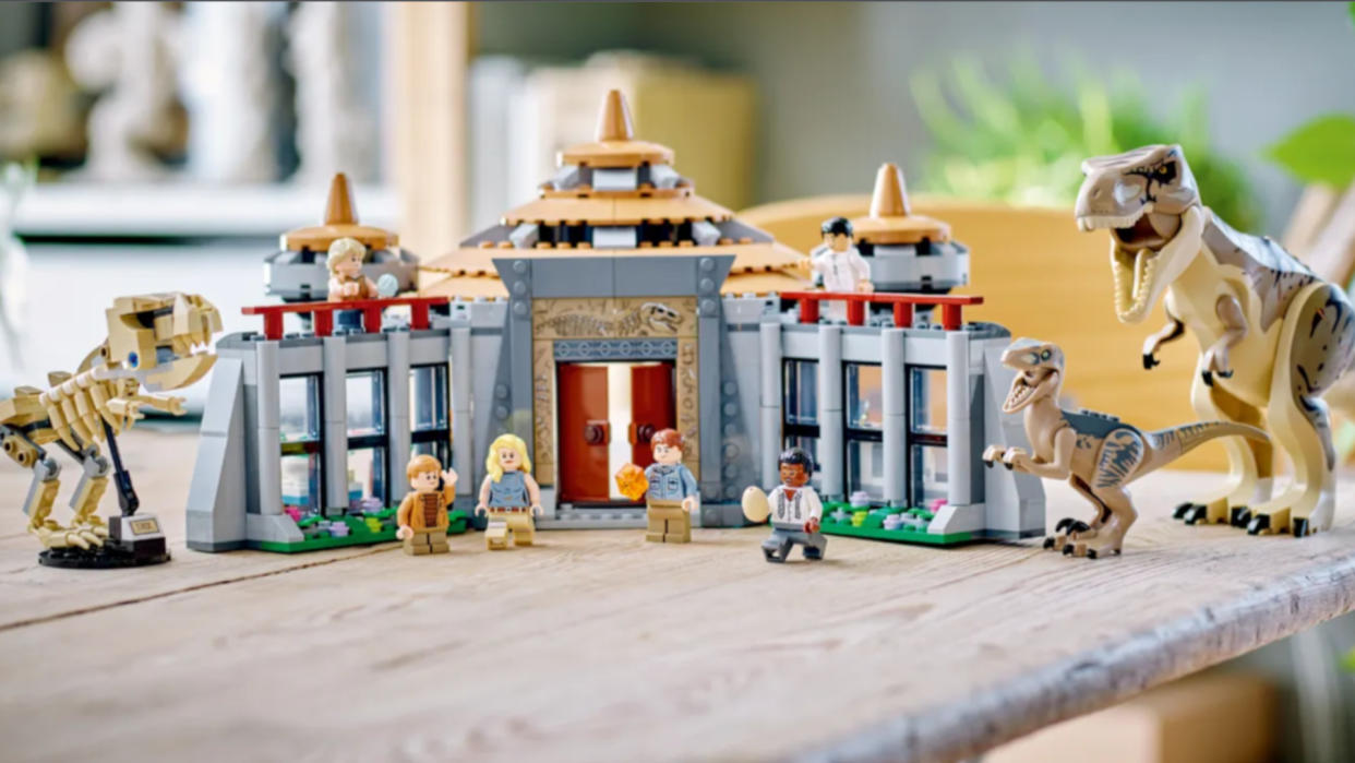  The fully-constructed Lego Visitor Center with all the Minifigures, arrayed on a wooden table 