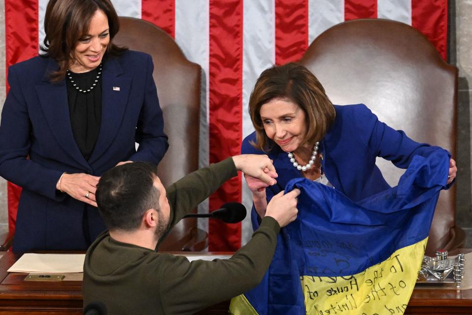 Ukrainian President Volodymyr Zelensky gives a Ukrainian flag to House Speaker Nancy Pelosi as Vice President Kamala Harris looks on.