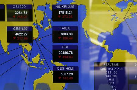 A passer-by is reflected on a panel displaying Asian stock market indexes, at the Hong Kong Stock Exchanges in Hong Kong, China January 7, 2016. REUTERS/Bobby Yip