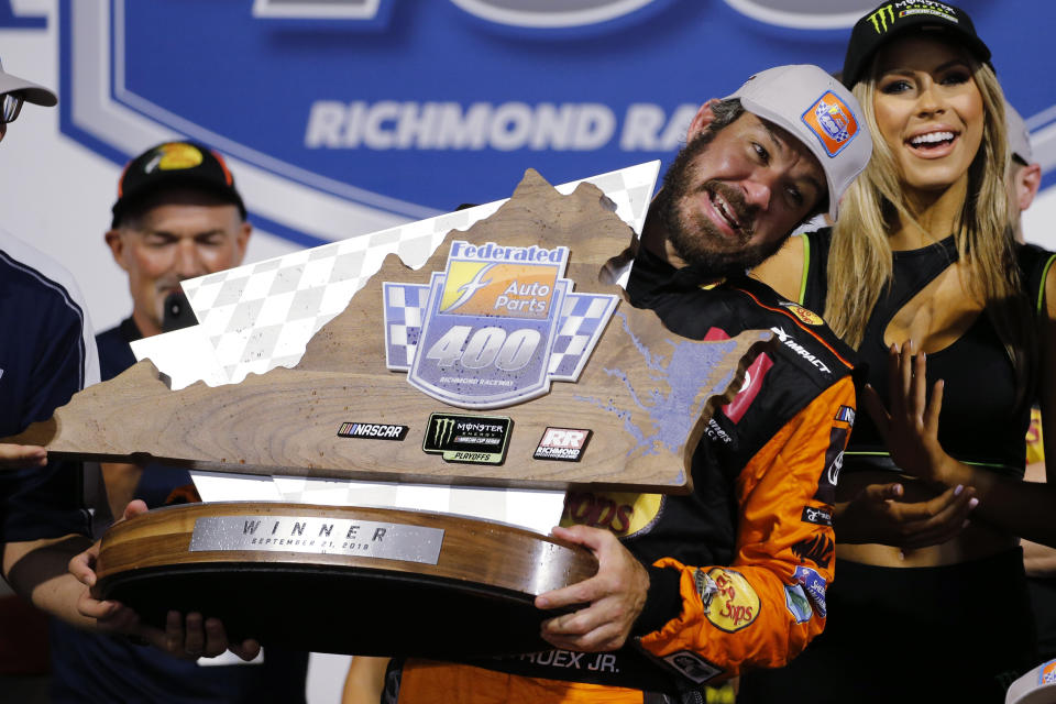 Martin Truex Jr. struggles to lift the winner's trophy after his victory in the NASCAR Cup Series auto race at Richmond Raceway in Richmond, Va., Saturday, Sept. 21, 2019. (AP Photo/Steve Helber)