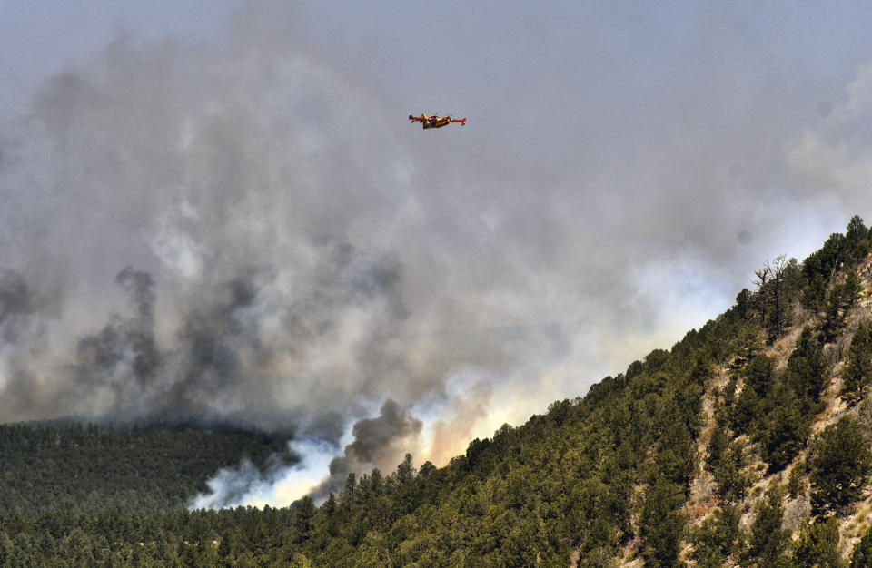 A firefighting plane flies over a plume of smoke near Las Vegas, N.M. on Wednesday, May 4, 2022. The fire has torched 250 square miles (647 square kilometers) over the last several weeks. (AP Photo/Thomas Peipert)