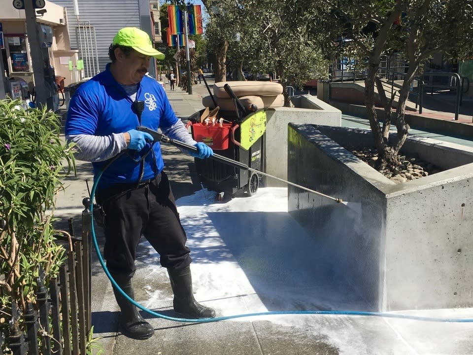 A Castro CBD cleaning crew member, power-washing at Jane Warner Plaza.