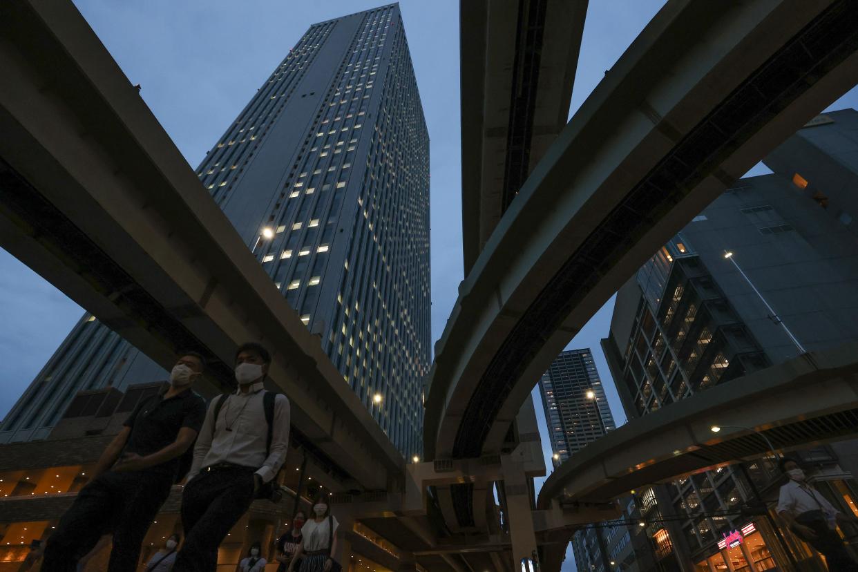 Pedestrians wearing protective masks cross a road in front of Sunshine 60 Building on July 21, 2020 in Tokyo, Japan.