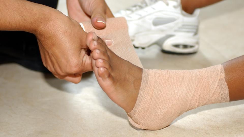 Person wrapping injured ankle with supportive bandage