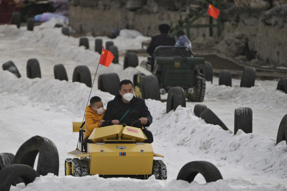 Residents ride on toy tanks in the snow at a public park in Beijing, Thursday, Jan. 19, 2023. China on Thursday accused "some Western media" of bias, smears and political manipulation in their coverage of China's abrupt ending of its strict "zero-COVID" policy, as it issued a vigorous defense of actions taken to prepare for the change of strategy. (AP Photo/Andy Wong)