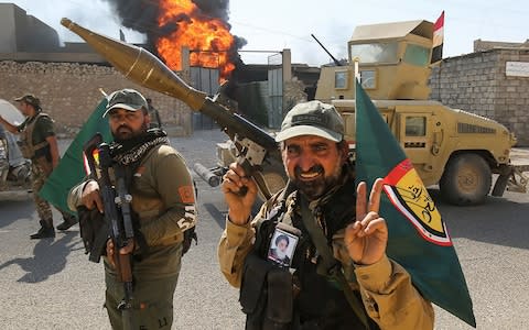 Fighters of the Popular Mobilisation Forces flash the victory gesture as they advance through a street in the town of Tal Afar, west of Mosul, after the Iraqi government announced the launch of the operation to retake it from Isil - Credit: AFP