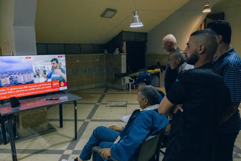 A group of Palestinian workers from Gaza at the Sarriyeh sports club in the West Bank city of Ramallah watch an Al Jazeera news broadcast on Oct. 12. <span class="copyright">Maen Hammad</span>