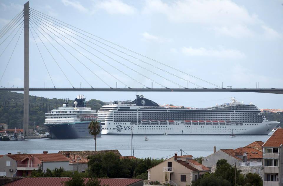 In this Sept. 7, 2018 photo, a cruise ship sails off as another one is moored in Dubrovnik. Crowds of tourist are clogging the entrances into the ancient walled city, a UNESCO World Heritage Site, as huge cruise ships unload thousands more daily. (AP Photo/Darko Bandic)