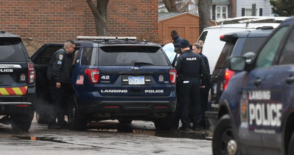 Members of the Lansing Police Dept. take a "person of interest" into custody near an apartment complex in the 3200 block of South Washington Avenue Friday morning, April 8, 2022. Police say a 39-year-old man was shot and killed just north of the building.