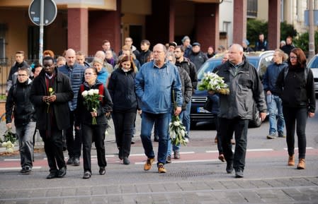 People holding flowers arrive to gather outside a kebab shop in Halle