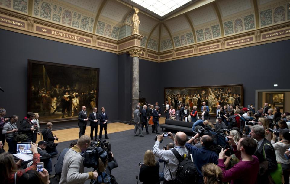 Journalists take pictures and video footage as dignitaries including museum director Wim Pijbes, center, pose in front of Dutch master Rembrandt's The Night Watch painting during a press preview of the renovated Rijkmuseum in Amsterdam, Thursday, April 4, 2013. The Rijksmuseum, home of Rembrandt's Night Watch and other national treasures, is preparing to reopen its doors on April 13 2013 after a decade-long renovation. (AP Photo/Peter Dejong)