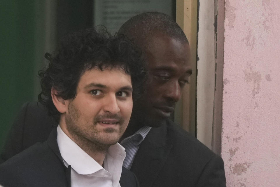 FTX founder Sam Bankman-Fried, is escorted from the Magistrate Court in Nassau, Bahamas, Wednesday, Dec. 21, 2022, after agreeing to be extradited to the U.S. (AP Photo/Rebecca Blackwell)