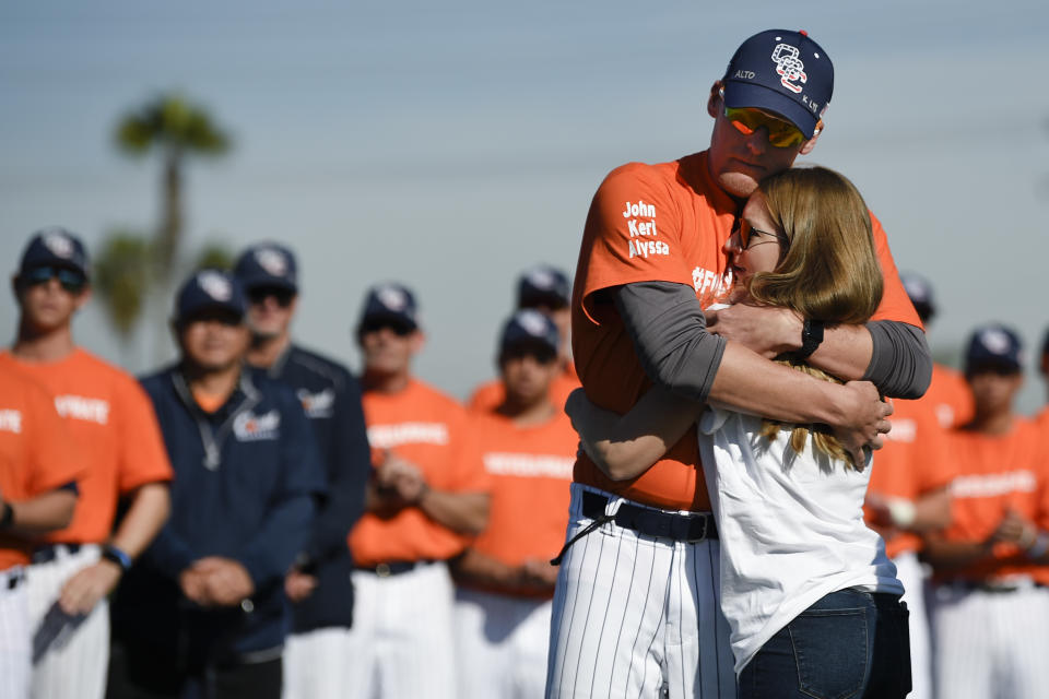 Associate coach Nate Johnson, left, embraces his wife Jonai during a ceremony held for John Altobelli, the late head coach of Orange Coast College baseball, who died in a helicopter crash alongside former NBA basketball player Kobe Bryant in Costa Mesa, Calif., Tuesday, Jan. 28, 2020. His wife Keri and youngest daughter Alyssa were also victims of the crash. (AP Photo/Kelvin Kuo)