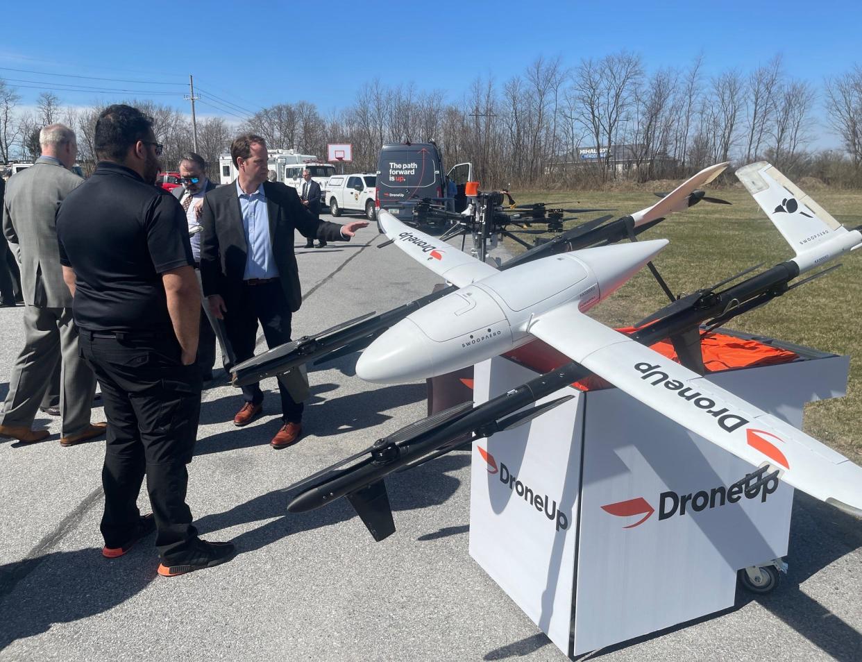 George Rodriguez, foreground left, and Greg James, center, explain how these two drones could potentially deliver medical supplies in an emergency situation. Both men work for DroneUp, a drone delivery service company from Virginia.