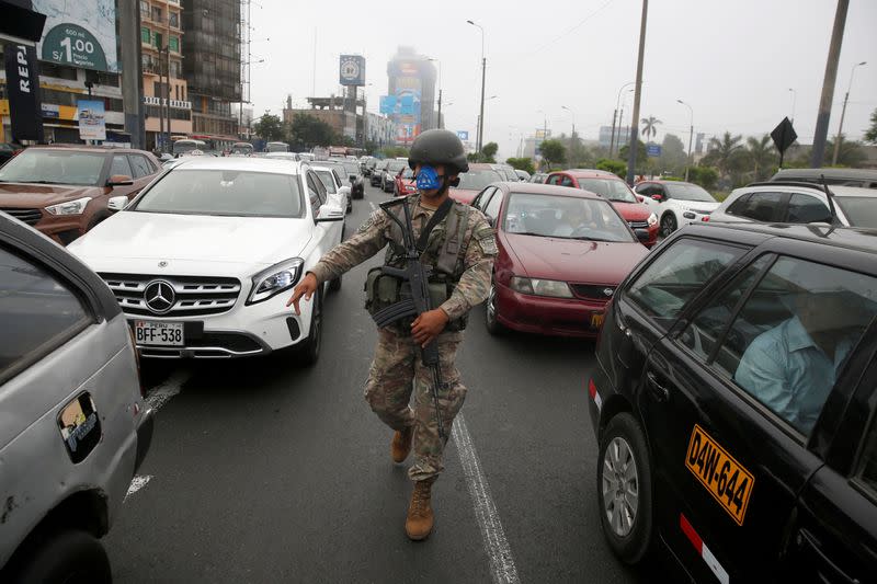 A soldier checks drivers' documents after Peru's government deployed military personnel to block major roads, as the country rolled out a 15-day state of emergency to slow the spread of coronavirus disease (COVID-19), in Lima