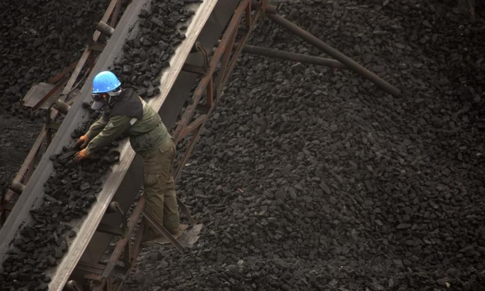 A worker monitors coal being carried along conveyor ramps at a coalmine in northern China.