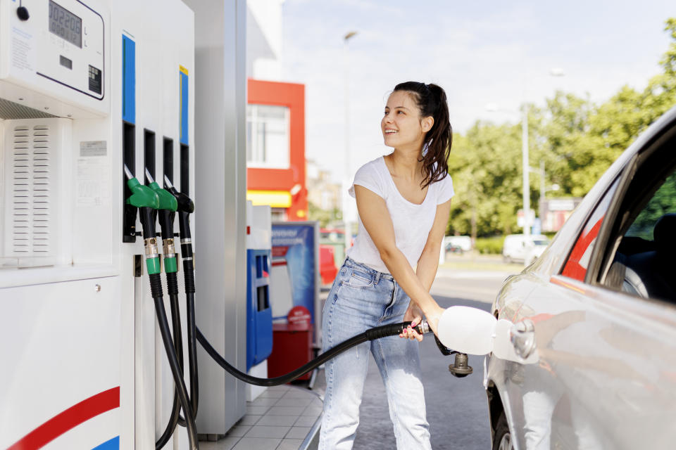 Smiling woman refueling the gas tank at fuel pump