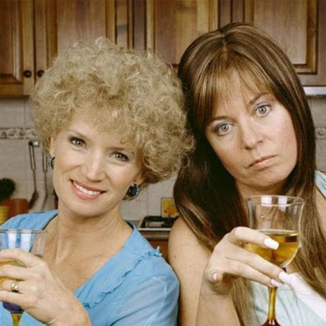 Kath and Kim on the set of their show, holding wine. 
