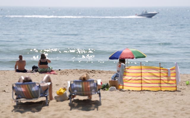 People in deckchairs enjoying the sunny weather on Bournemouth Beach