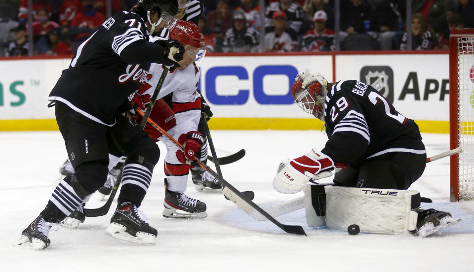 Carolina Hurricanes center Paul Stastny tries to skate past New Jersey Devils defenseman Jonas Siegenthaler, left, as Devils goalie Mackenzie Blackwood (29) makes the save during the second period of an NHL hockey game Sunday, Jan. 1, 2023, in Newark, N.J. (AP Photo/John Munson)