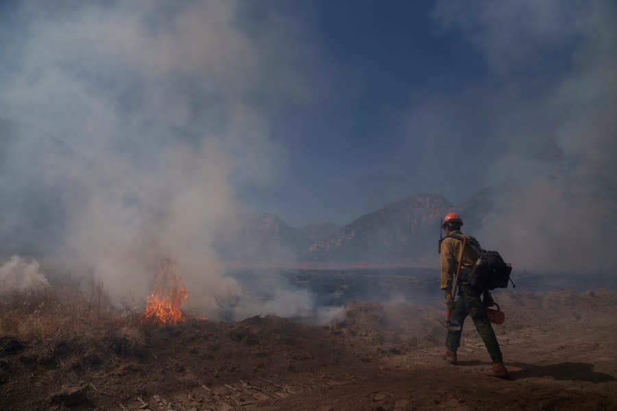 A firefighter walks towards flames from the Post Fire on Sunday, June 16, 2024, in Lebec, Calif. (AP Photo/Eric Thayer)