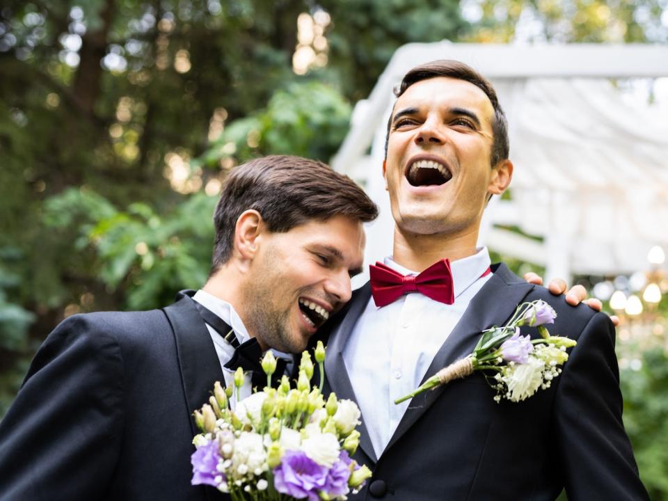Two grooms laugh together on their wedding day.