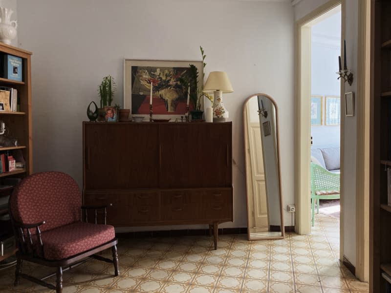 white entryway with wood bureau, tile floor, armchair and mirror
