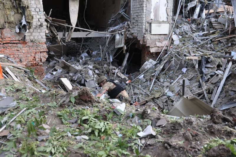 A law enforcement officer examines a crater in an office building that was destroyed by a Russian missile strike in the center of Kharkiv in northeastern Ukraine. -/Ukrinform/dpa