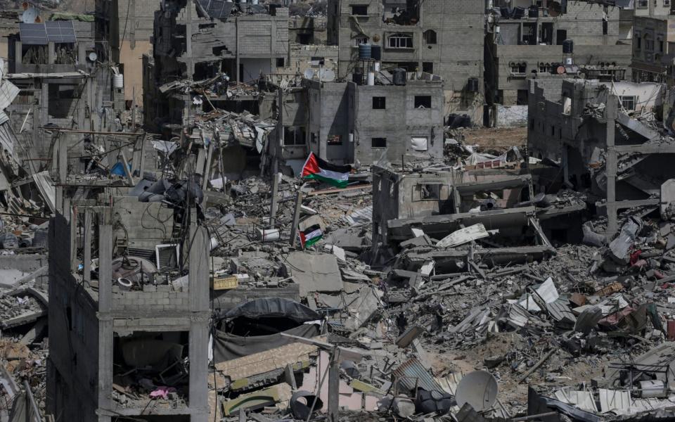 The Palestinian flag flies surrounded by the rubble of destroyed buildings following an Israeli military operation in Khan Younis