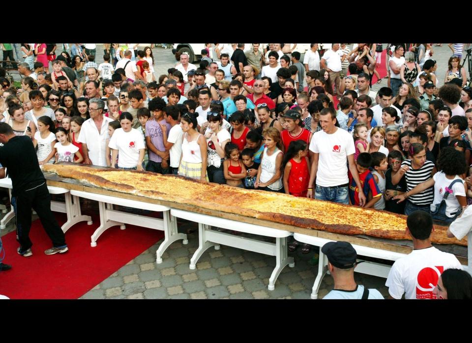 People look at a huge khachapuri (Georgian cheese pastry) in central Batumi on July 28, 2011. The cake was baked using 100 eggs, 90 kilograms of cheese, 150 kilograms of flour, has 8 meters length and was eaten within 1minute 32 seconds by people at a street.