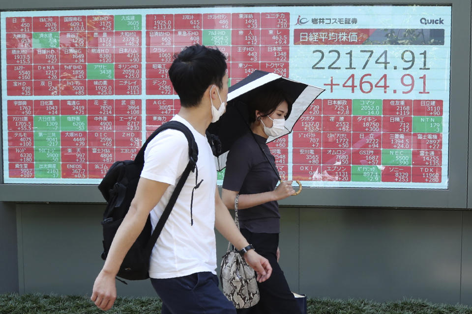 People wearing face masks walk by an electronic stock board of a securities firm in Tokyo, Monday, Aug. 3, 2020. Asian shares were mixed on Monday, as investors watched surging numbers of new coronavirus cases in the region, including in Japan. (AP Photo/Koji Sasahara)