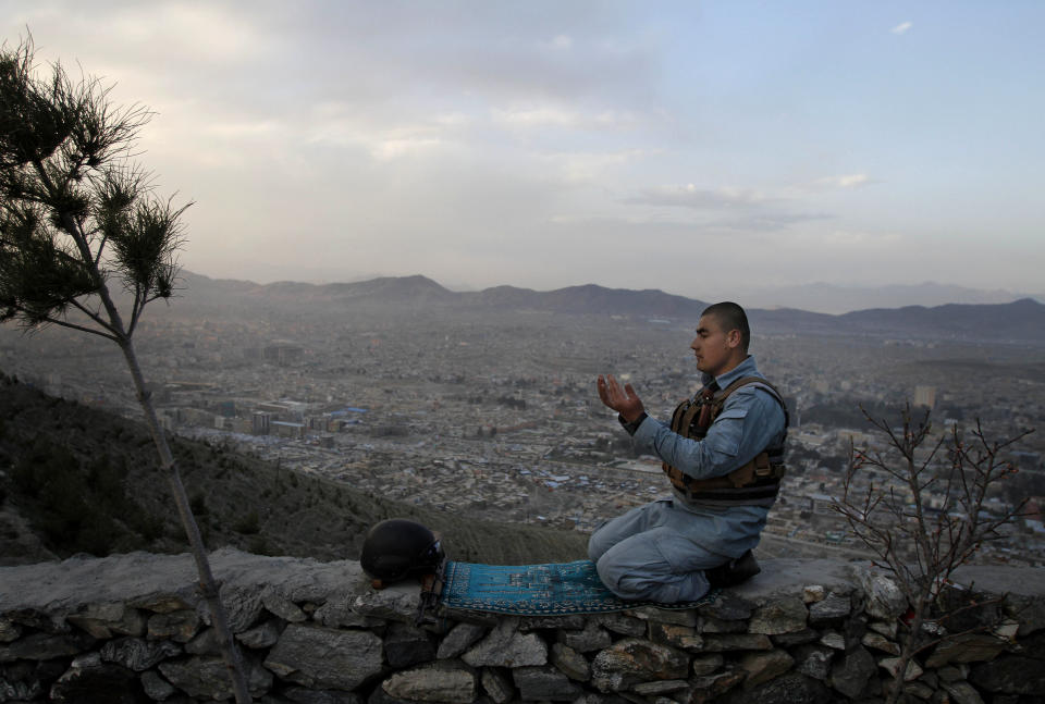 FILE - In this Sunday, March 31, 2013 file photo, an Afghan police man offers evening prayers on a hill overlooking Kabul, Afghanistan. As the country braces for next year's presidential election and the planned withdrawal of most foreign combat troops by the end of 2014, the panel urges the U.S. government and its allies to work harder to promote religious rights in the war-torn nation. (AP Photo/Ahmad Jamshid, File)