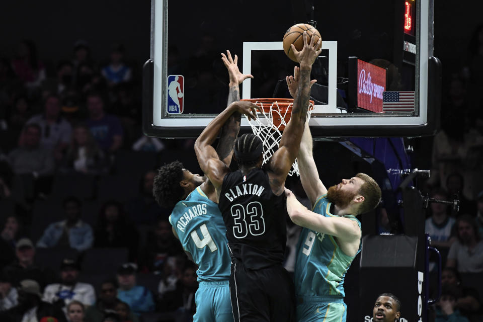 Charlotte Hornets center Nick Richards (4) and forward Davis Bertans (9) attempt to block a shot by Brooklyn Nets center Nic Claxton (33) during the first half of an NBA basketball game, Saturday, March 9, 2024, in Charlotte, N.C. (AP Photo/Matt Kelley)