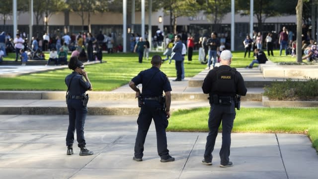 Houston Police officers watch over churchgoers outside Lakewood Church in Houston after a shooting inside the church.