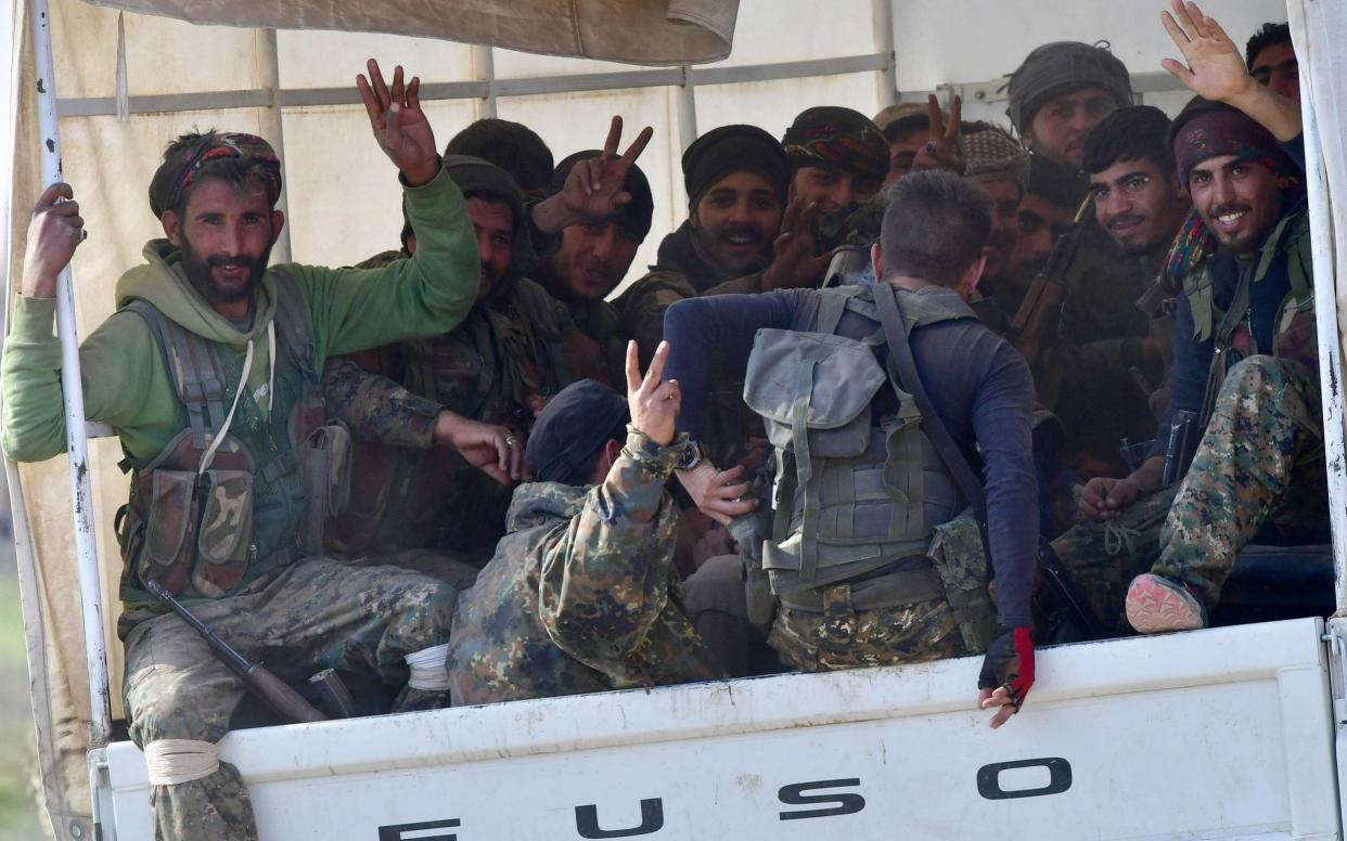 Fighters from the Syrian Democratic Forces (SDF) gesture the