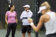 Lan Yao-Gallop, left, talks with coach Mark Gellard as Magda Linette prepares to serve on a practice court at the Charleston Open tennis tournament in Charleston, S.C., Monday, April 3, 2023. Yao-Gallop is a participant in the women’s professional tennis tour’s Coaching Inclusion Program to develop female coaches. (AP Photo/Mic Smith)