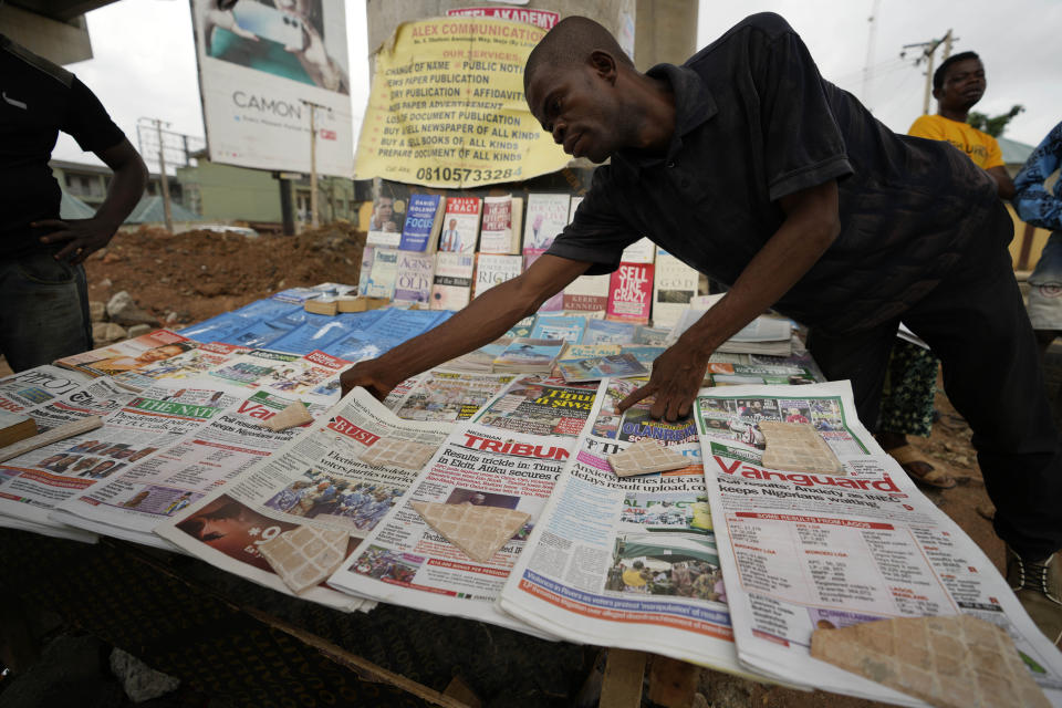 A man arranges local newspapers with preliminary presidential election results on a street in Lagos, Nigeria, Monday, Feb. 27, 2023. Each of the three frontrunners in Nigeria's hotly contested presidential election claimed they were on the path to victory Monday, as preliminary results trickled in two days after Africa's most populous nation went to the polls. (AP Photo/Sunday Alamba)