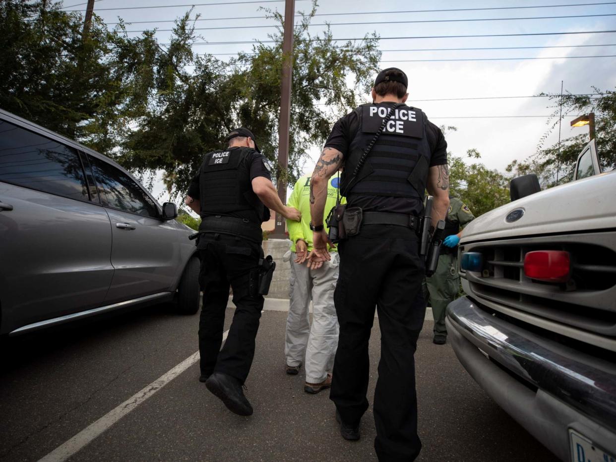 Immigration and Customs Enforcement (ICE) agents escort a man in handcuffs: AP