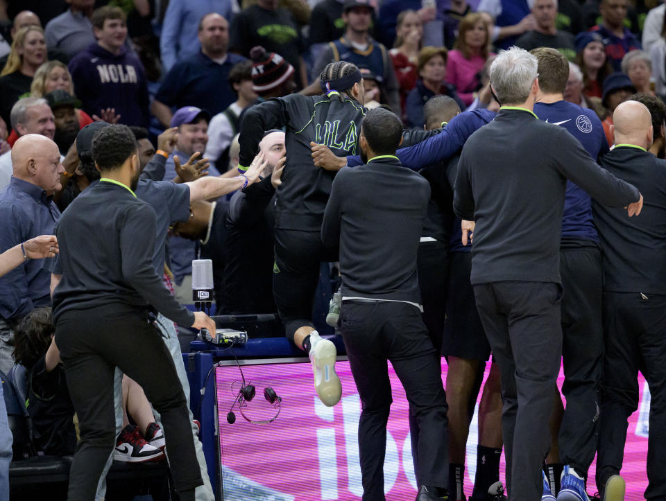 New Orleans Pelicans guard Jose Alvarado, center top, climbs on the scorer's table after getting in a scuffle with Miami Heat center Thomas Bryant (not shown) during the second half of an NBA basketball game in New Orleans, Friday, Feb. 23, 2024. Alvarado and Bryant were ejected from the game. (AP Photo/Matthew Hinton)