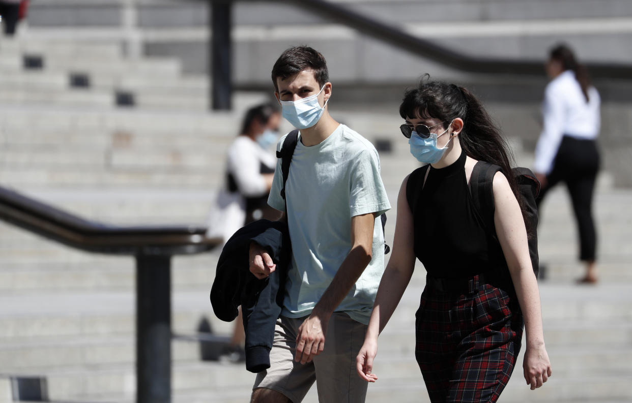 A couple of pedestrian walk through Trafalgar Square waering masks to help combat COVID-19 in London, Thursday, July 30, 2020.(AP Photo/Alastair Grant)