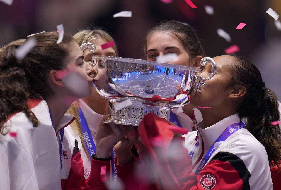 Canada's Leylah Fernandez, right, kisses the trophy with members of her team after wining the final singles tennis match against Italy's Jasmine Paolini, during the Billie Jean King Cup finals in La Cartuja stadium in Seville, southern Spain, Spain, Sunday, Nov. 12, 2023. (AP Photo/Manu Fernandez)