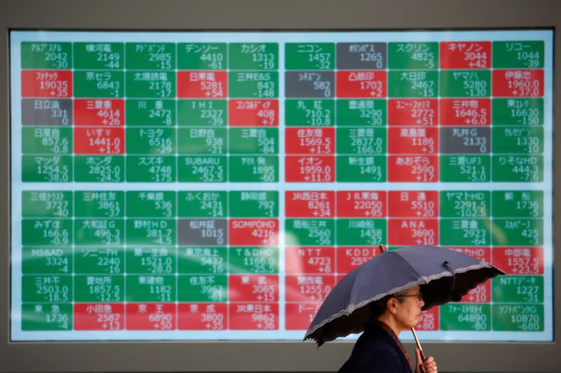 A passerby walks past in front of a stock quotation board outside a brokerage in Tokyo