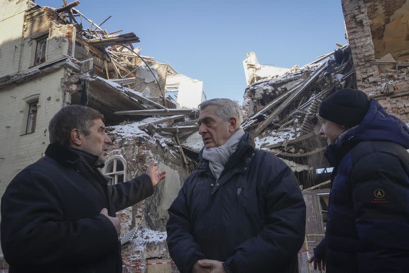 United Nations High Commissioner for Refugees Filippo Grandi, centre, listens to a local resident as he visits sites of recent bombings in Kharkiv, Ukraine, Monday, Jan. 22