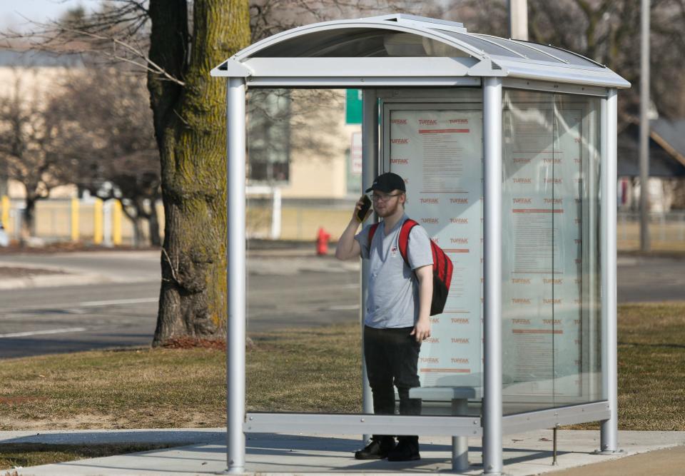 Lansing Eastern junior Nick Doing waits for the CATA bus outside Lansing Eastern High School on Tuesday, Feb. 27, 2024. He takes the bus to work downtown.