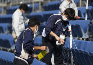 Stadium crew members install a device to detect carbon dioxide in the seats of a baseball stadium, home for the Yokohama DeNA BayStars, in Yokohama, south of Tokyo on Friday, Oct. 30, 2020. The device was introduced during a media tour before a Japanese professional baseball league game between the Hanshin Tigers and the DeNA BayStars on Friday. (AP Photo/Hiro Komae)